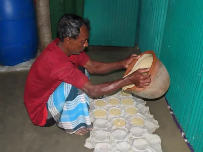 হাজারী গুড়ের পাটালীর আকার দিতে, ছোট ছোট মাটির বাটিতে শুকনো কাপড়ের উপর তরল গুড় ঢালা হচ্ছে।