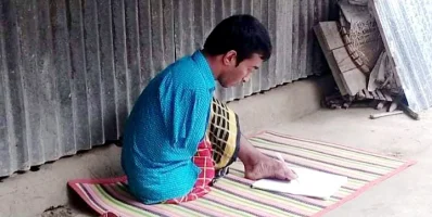 পা দিয়ে লিখছেন ফজলুর রহমান। ছবি: ইত্তেফাক