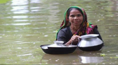 নিজ বাড়িতে পানি থাকায় রান্নার জন্য উঁচু স্থানে যাচ্ছেন এক নারী। 