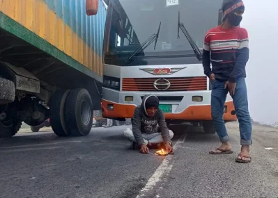 যানজটে পড়ে গাড়ি থেকে নেমে আগুন জ্বালিয়ে শীত নিবারণের চেষ্টা। ছবি: ইত্তেফাক