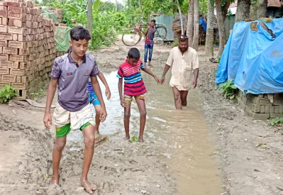 লুঙ্গি কাছা দিয়ে সড়কের গর্ত পাড় হচ্ছেন পথচারী। ছবি: ইত্তেফাক