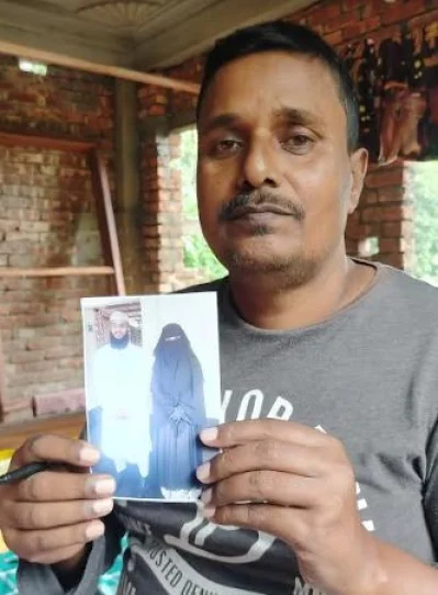 চিকিৎসক ছেলে ও বউমার ছবি হাতে বাবা হেলাল উদ্দিন। ছবি: ইত্তেফাক