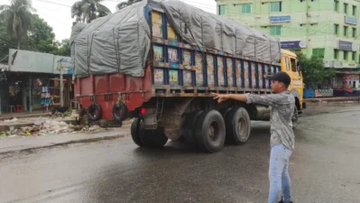 হাতের ইশারা দিয়ে সড়কের যানবহন নিয়ন্ত্রণ করছেন এক শিক্ষার্থী । ছবি: ইত্তেফাক 