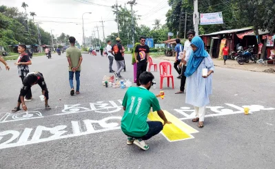  শিক্ষার্থীরা সড়কে সচেতনতামূলক বাণী লিখছেন । ছবি: ইত্তেফাক 