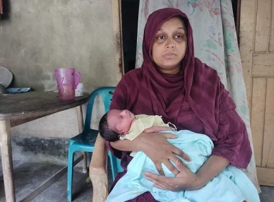  নবজাতক সন্তানকে নিয়ে বসে আছেন মাসুদের স্ত্রী বিউটি আরা। ছবি: সংগৃহীত 