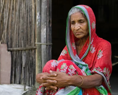 আসামে বাড়ির বাইরে বসে আছেন হাজেরা খাতুন, ৬২ বছর বয়সী এই নারীকে অন্যদের সাথে আটক করে বাংলাদেশে পাঠানো হয়েছিল। ছবি: সংগৃহীত