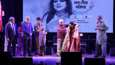 অনুষ্ঠানে সাবিনা ইয়াসমীনকে উত্তরীয় পরিয়ে দিচ্ছেন পরিকল্পনা উপদেষ্টা ওয়াহিদউদ্দিন মাহমুদ। ছবি: সংগৃহীত