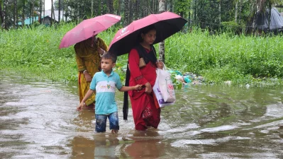 ছাতা দিয়ে বৃষ্টি থেকে বাঁচলেও রক্ষা হয়নি বন্যার পানি থেকে। সাতকানিয়া, চট্টগ্রাম